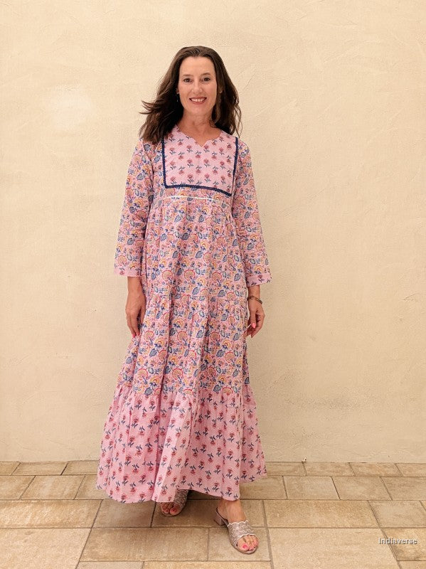 Woman wearing a floral dress standing against a beige wall.