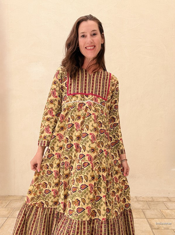 Woman wearing a long, patterned dress against a plain background