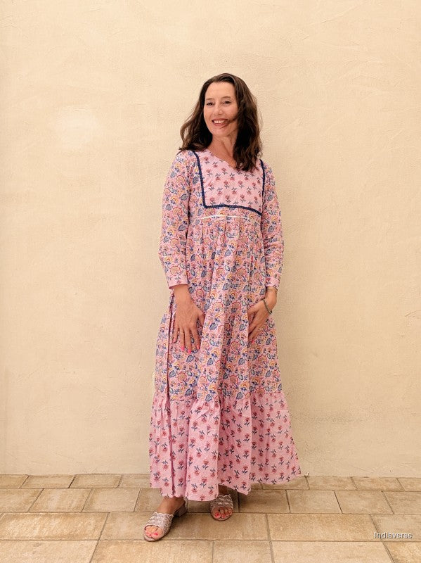 Woman wearing a pink floral dress standing against a beige wall.