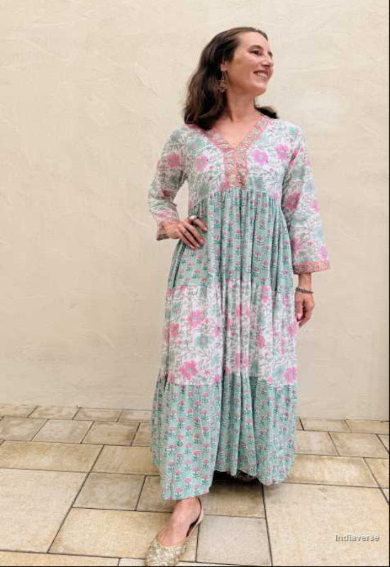 Woman wearing a floral dress standing against a beige wall.
