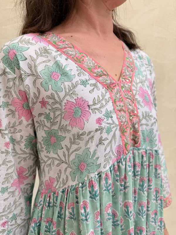 Person wearing a floral patterned dress with pink and green flowers.
