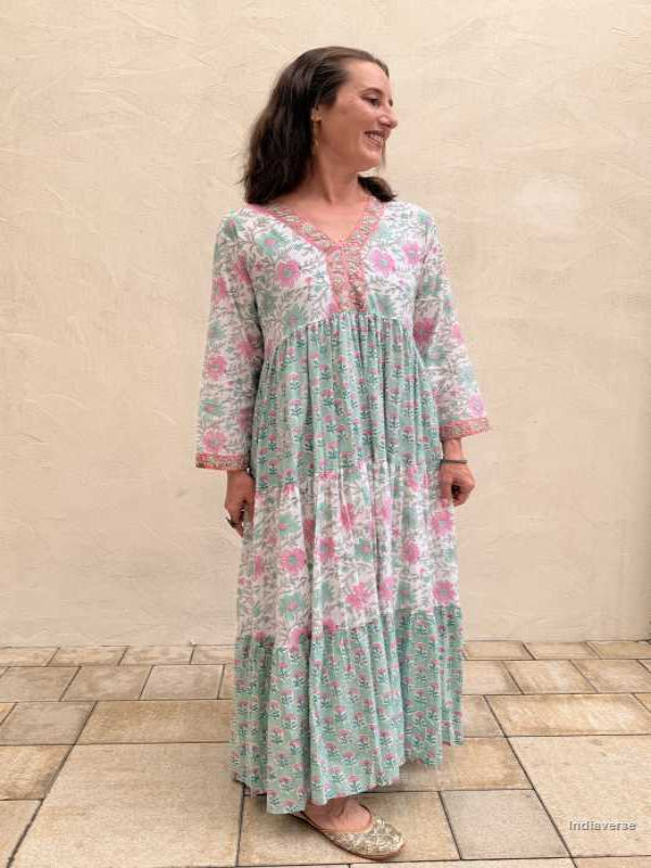 Woman wearing a floral dress standing against a beige wall.