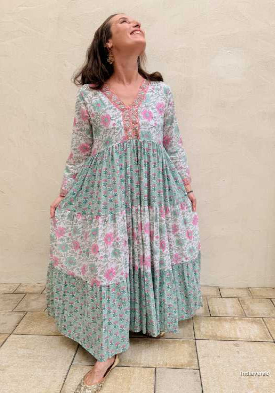 Woman wearing a floral dress standing against a beige wall.
