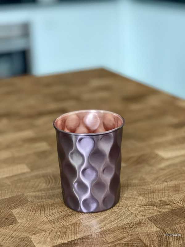 polished copper cup with hammered diamond shape details made for serving water and healthy alternative to glass