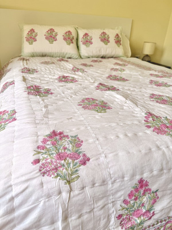 View of a bedroom styled with a white quilt with pink flower design and two matching pillowcases