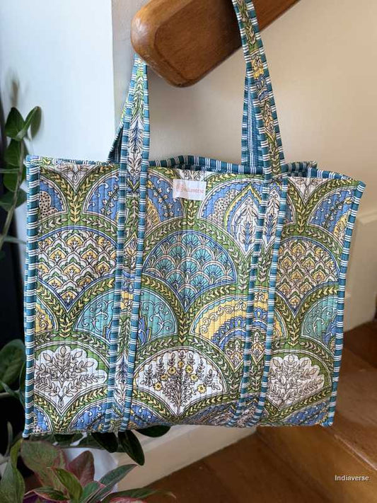 hand block printed quilted cotton tote bag with blue, yellow and green geometric design perfect for shopping and carrying essentials hanging on staircase railing