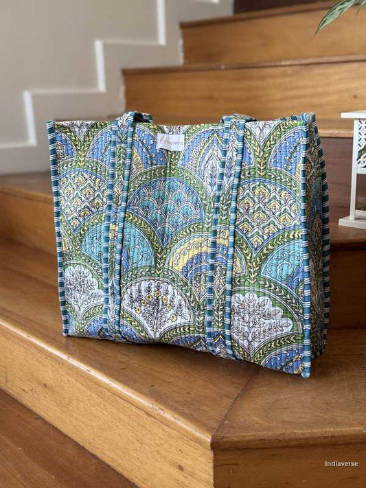 hand block printed quilted cotton tote bag with blue, yellow and green geometric design perfect for shopping and carrying essentials sitting on a wooden stair case