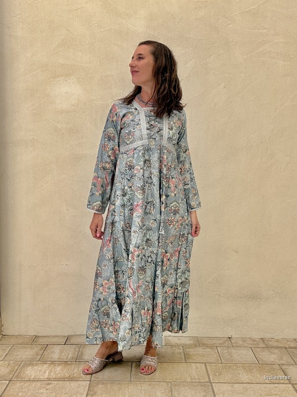 Woman wearing a floral dress standing against a beige wall.