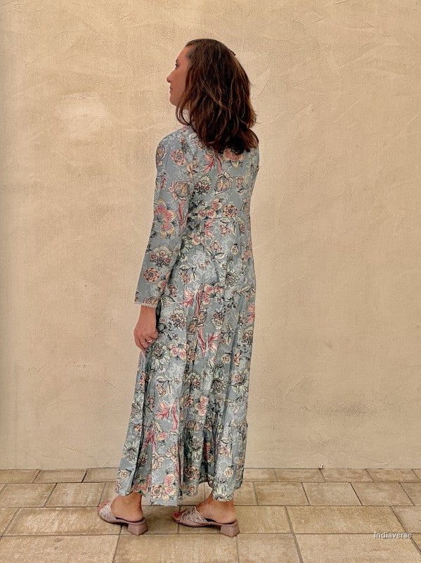 Woman wearing a floral dress standing against a beige wall.