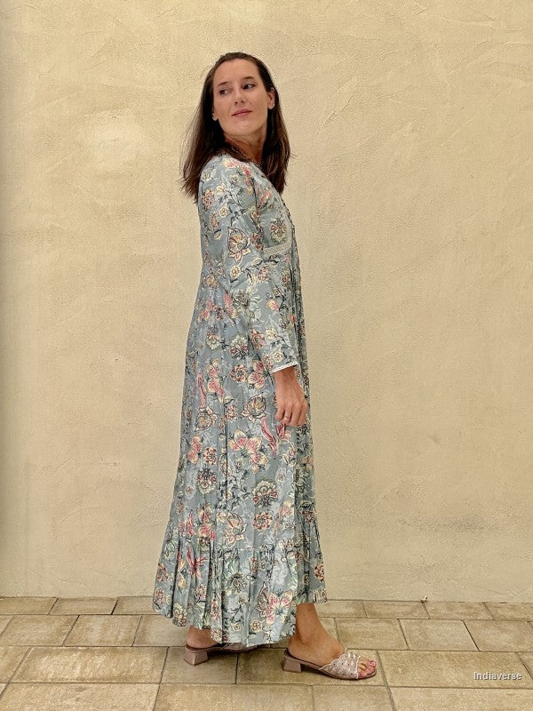 Woman wearing a floral dress standing against a beige wall.