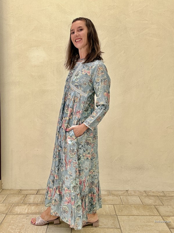 Woman wearing a floral dress standing against a beige wall.