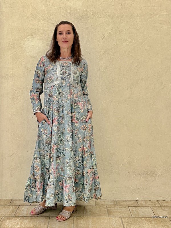 Woman wearing a floral dress standing against a beige wall.