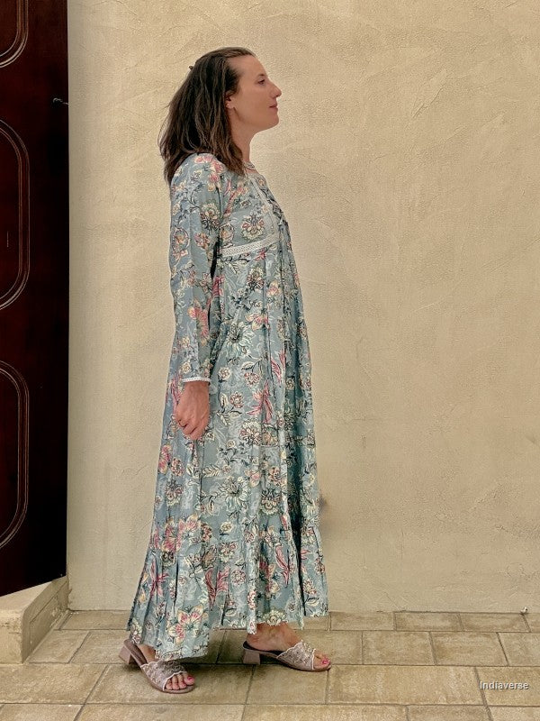 Woman wearing a floral dress standing against a beige wall.