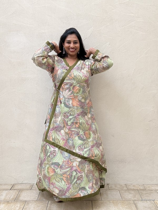 Woman wearing a green long dress standing against a beige wall
