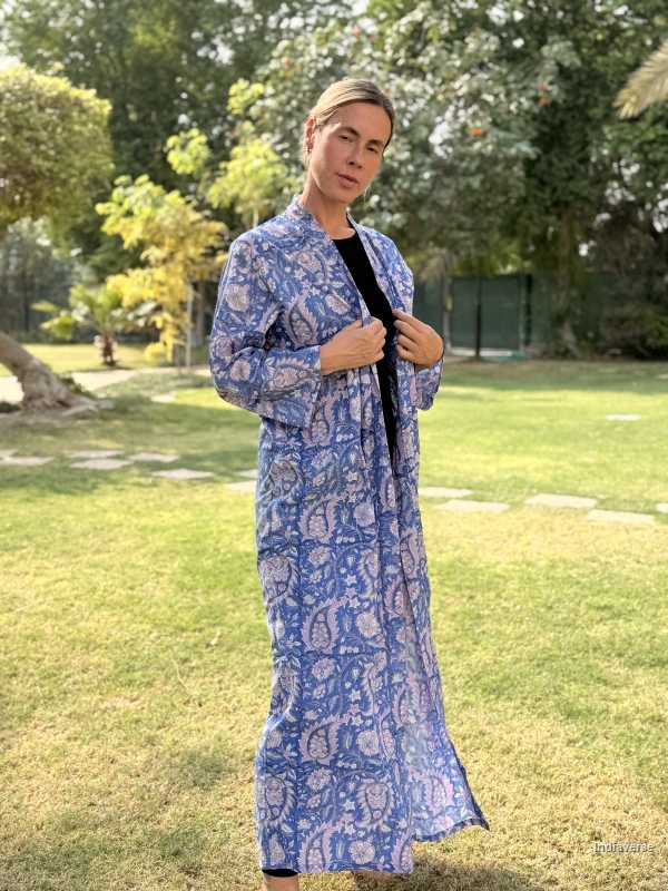 Person wearing a blue patterned dress standing in a park.