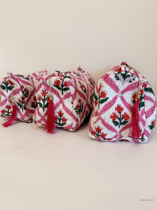 Three small drawstring pouches with embroidered floral and geometric patterns in pink, red, green, and white, each finished with a red tassel, displayed on a plain beige surface | Flower Candy