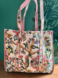 quilted tote bag with colorful floral design in front of green wall