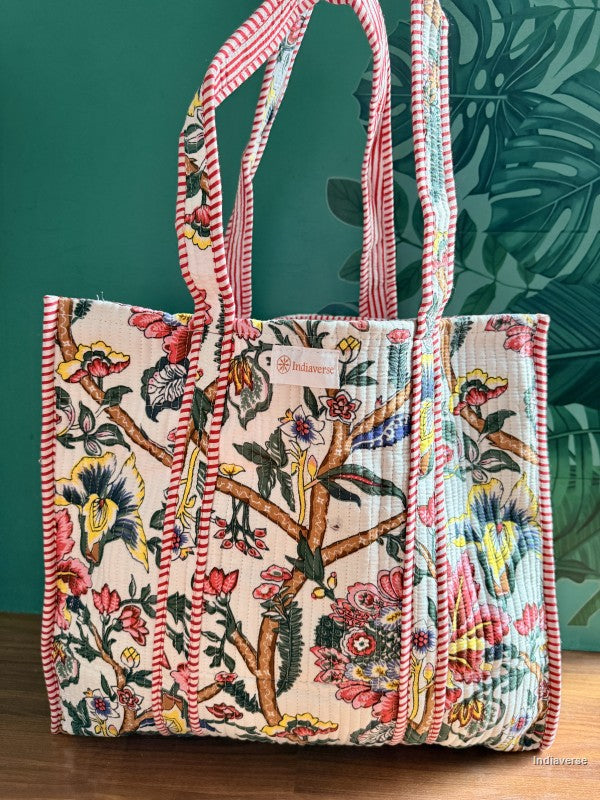 quilted tote bag with colorful floral design in front of green wall
