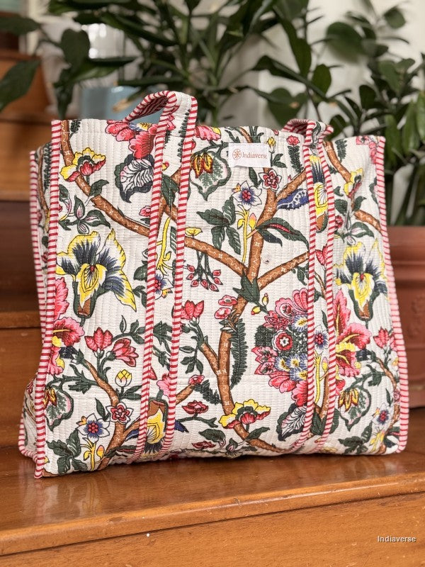 quilted tote bag with colorful floral design sitting on a wooden surface