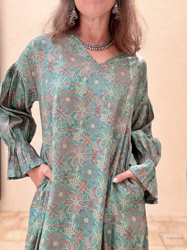 Woman wearing a floral patterned dress with long sleeves against a beige background