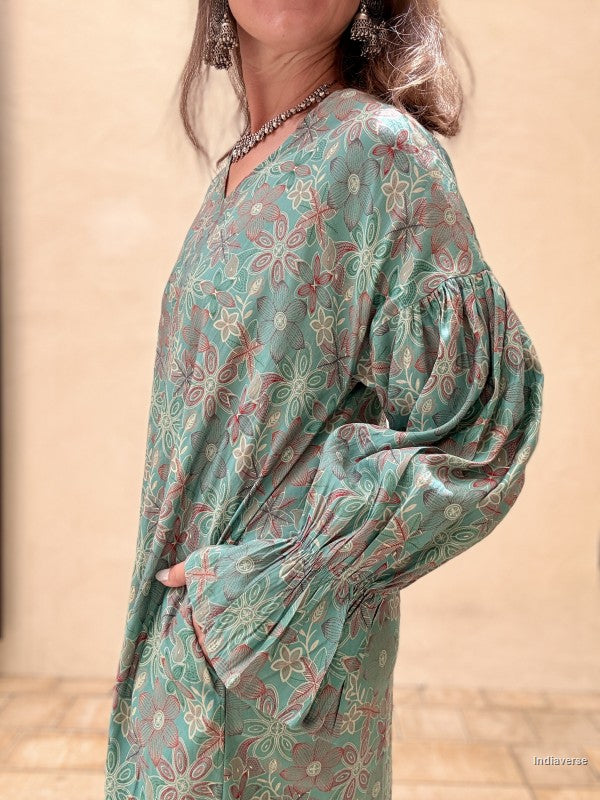 close up of teal green dress with long sleeves and floral star pattern