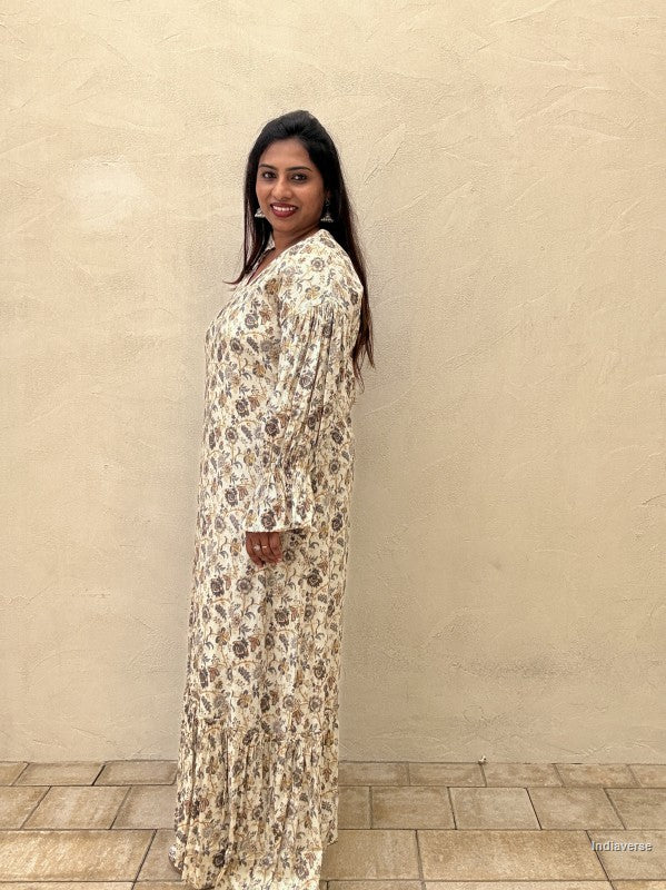Woman standing in front of a beige wall wearing a long flowing blue floral jalabiya dress
