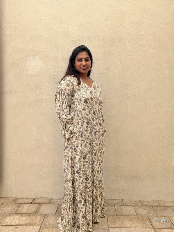 Woman wearing a floral dress standing against a beige wall.