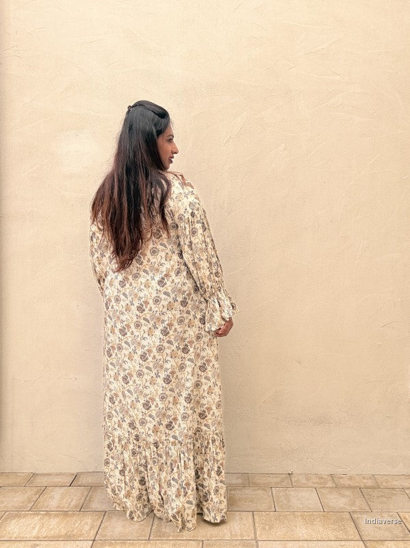Woman wearing a floral dress standing against a beige wall.