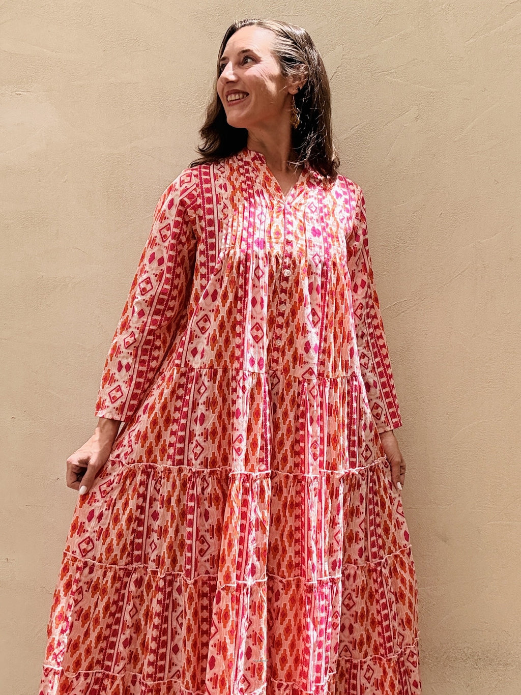 Woman wearing a red and white patterned dress against a beige wall