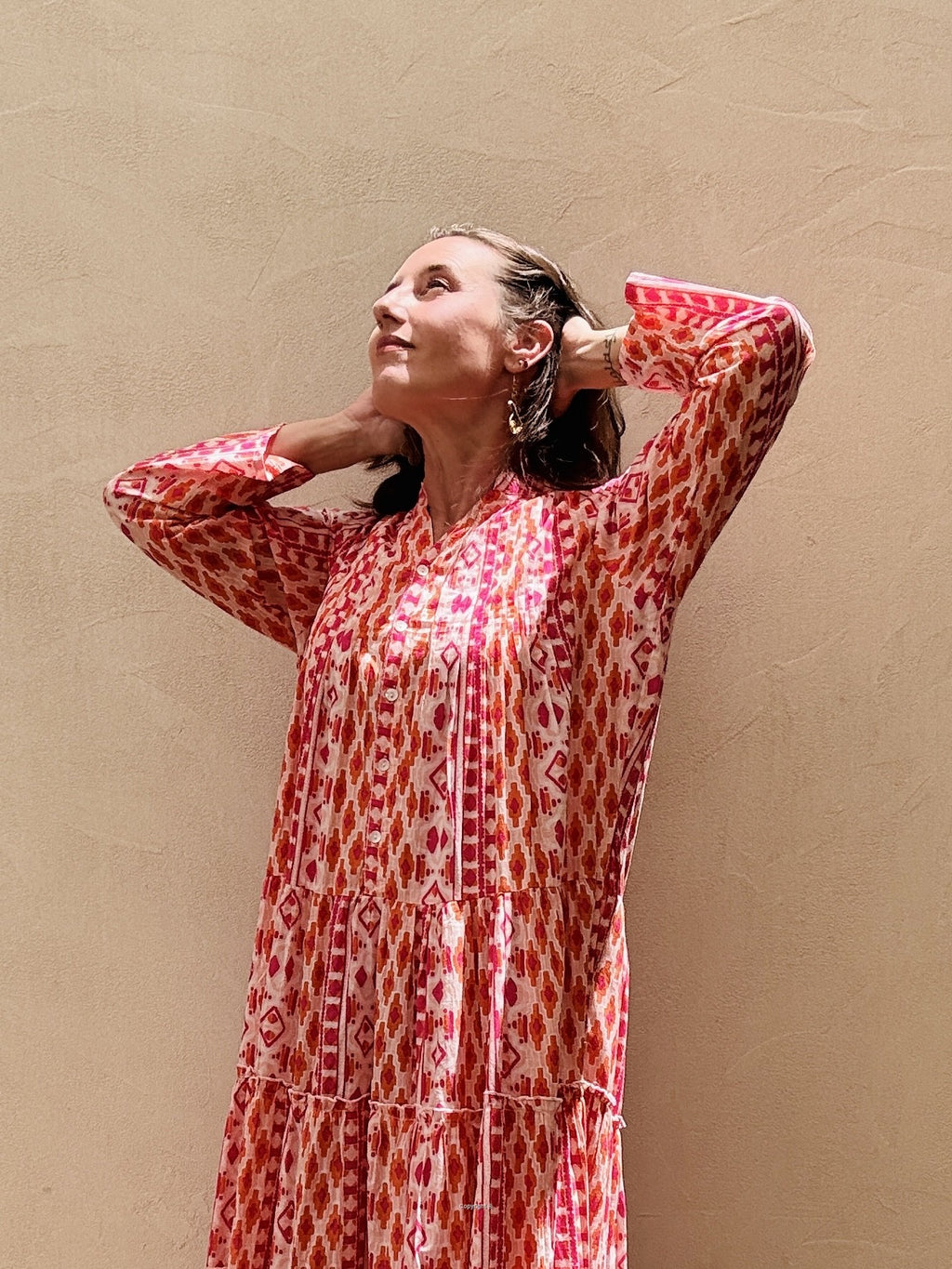 Woman wearing a red and white patterned dress against a beige wall