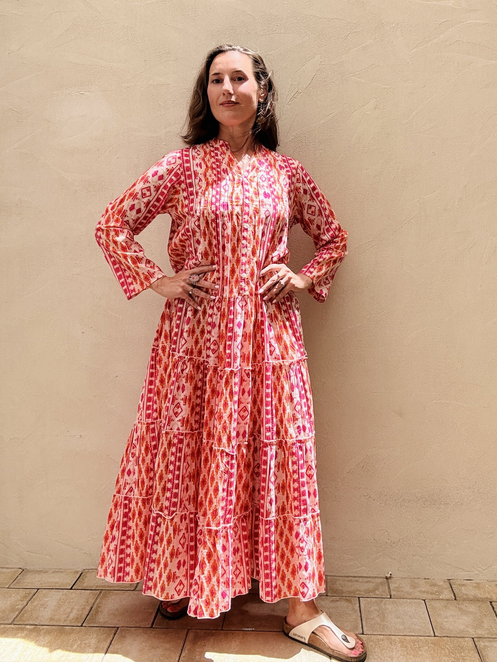 Woman wearing a red and white patterned dress against a beige wall.