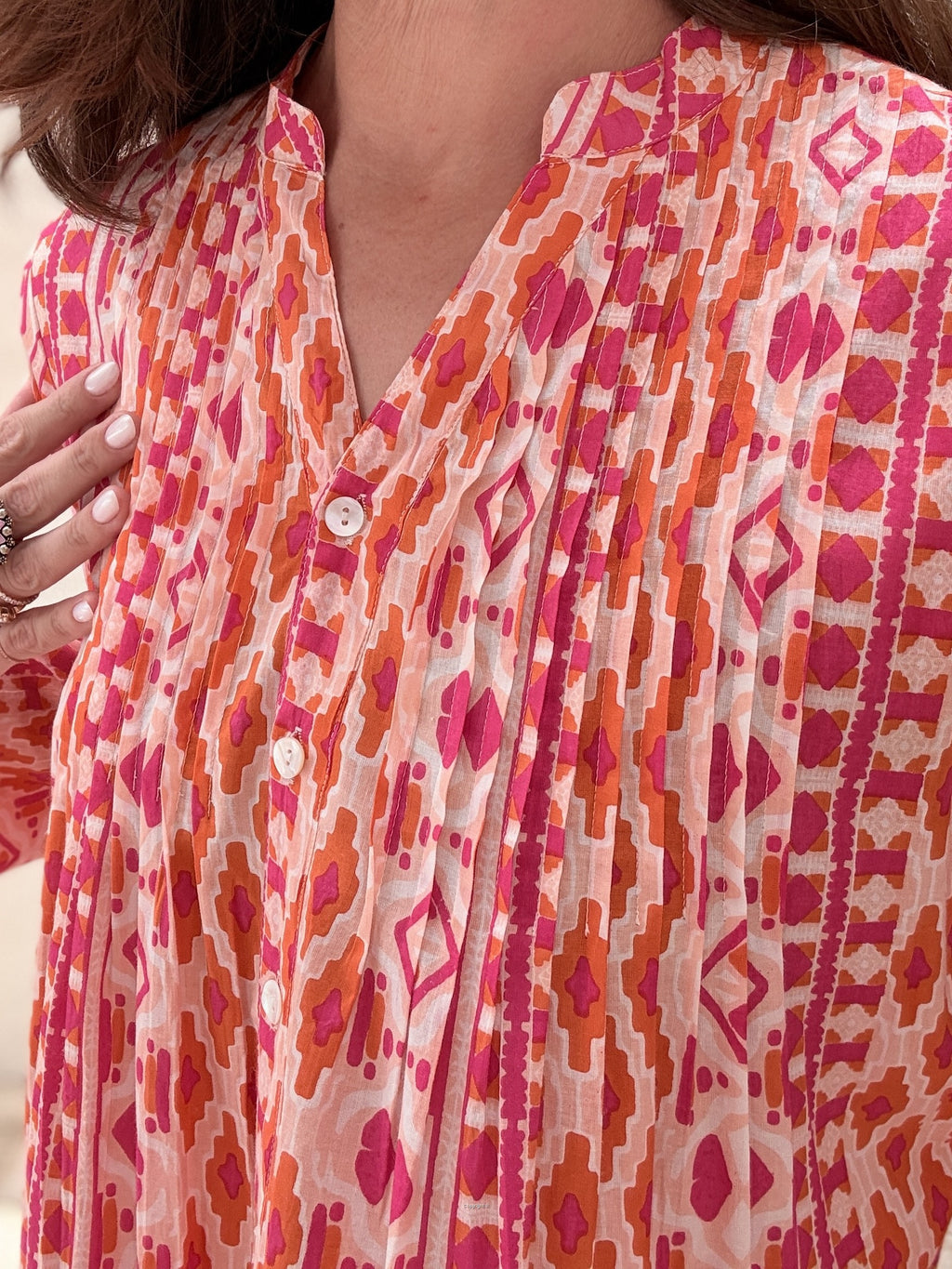 Close-up of a person wearing a patterned shirt with pink and orange design.