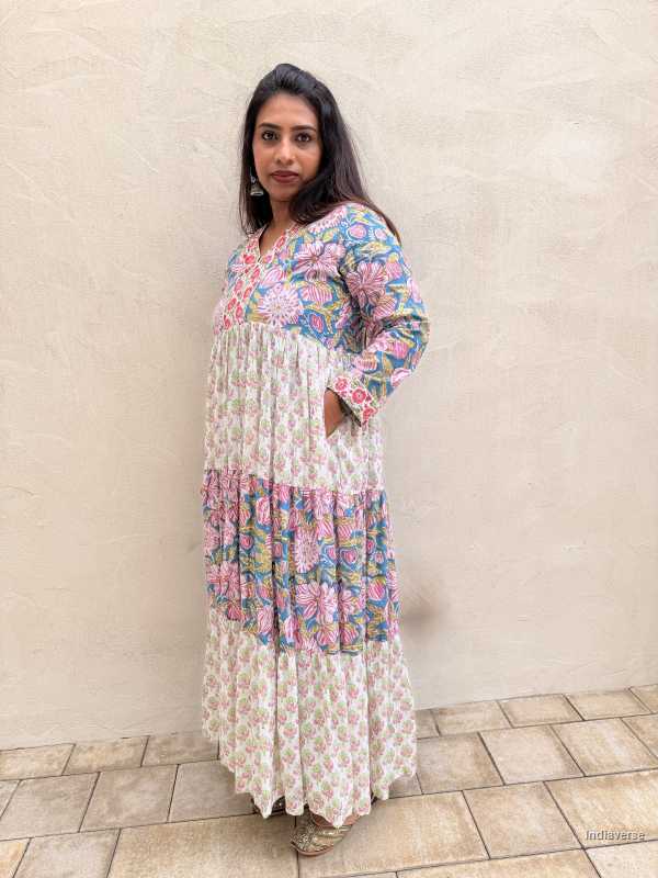 Woman wearing a floral dress standing against a light-colored wall.