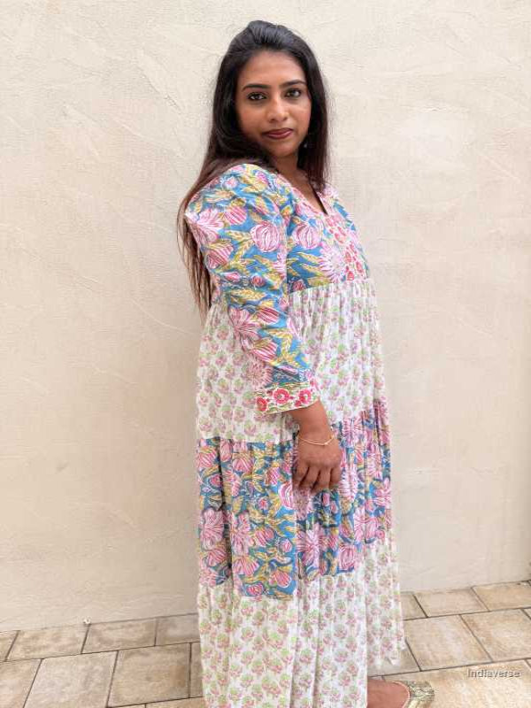 Woman wearing a floral dress standing against a beige wall.