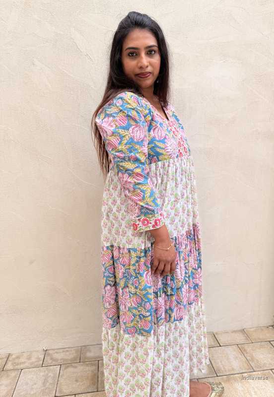 Woman wearing a floral dress standing against a beige wall.