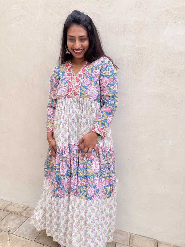 Woman wearing a floral dress standing against a beige wall