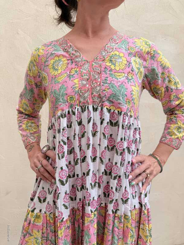 Person holding a pleated fabric with floral patterns on a beige background