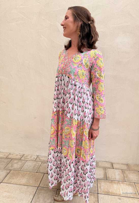 Woman wearing a floral dress standing against a beige wall.