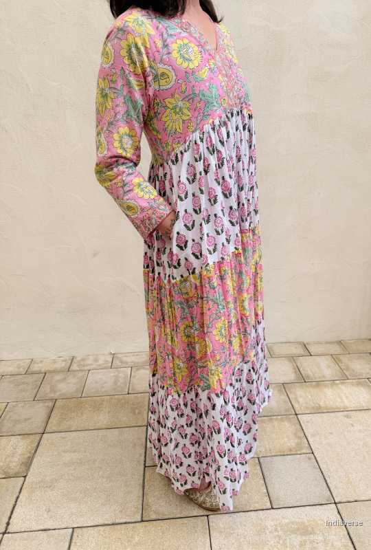 Person wearing a long, patterned dress with floral and abstract designs on a tiled floor.