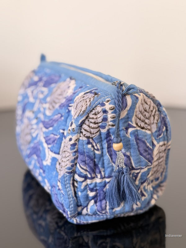 Blue and white patterned fabric bag with tassels on a plain background