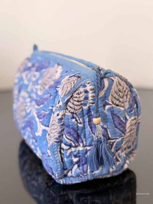 Blue and white patterned fabric bag with tassels on a plain background