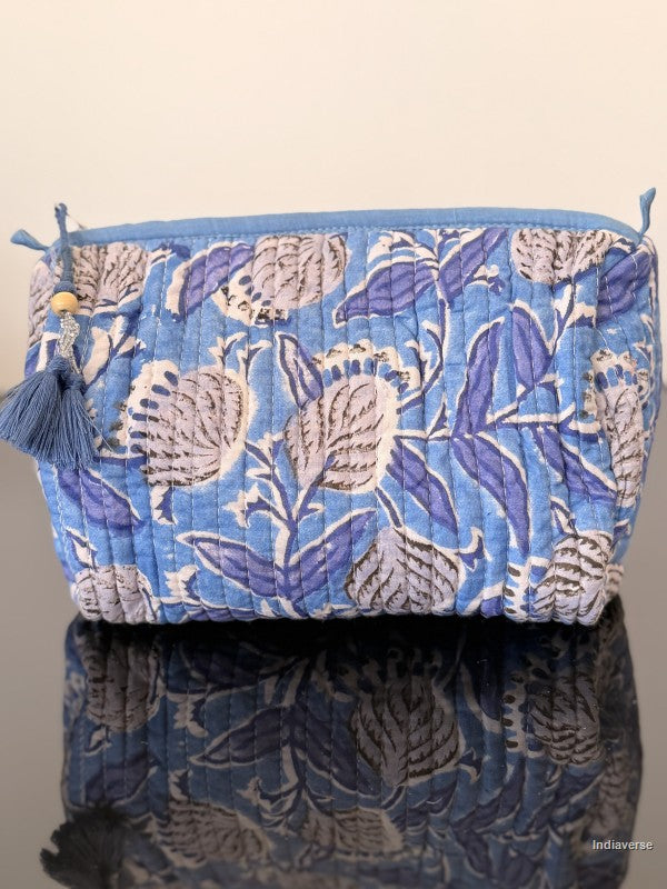 Blue floral patterned bag with tassels on a reflective surface