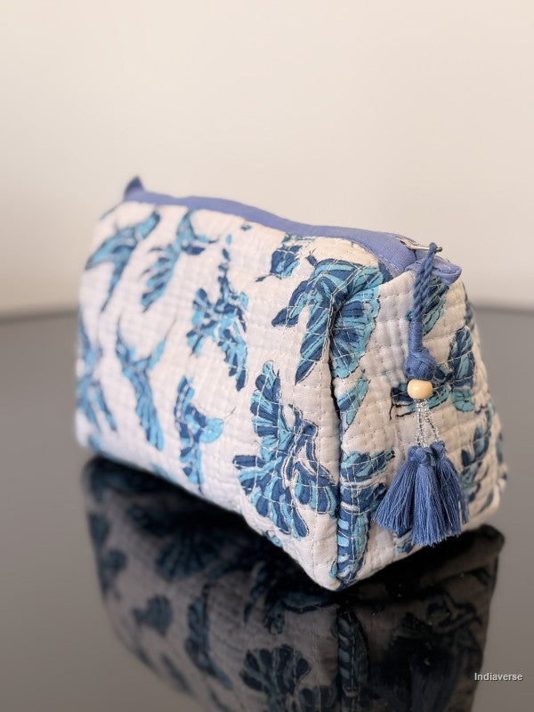white pouch with blue tassel and blue hummingbirds on a glass surface