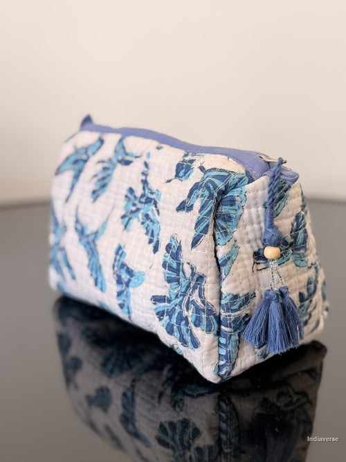 white pouch with blue tassel and blue hummingbirds on a glass surface