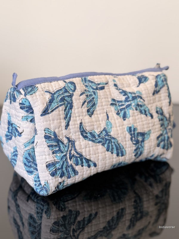 white pouch with blue hummingbirds sitting on a glass surface