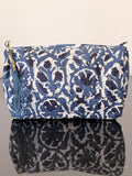 Blue and white patterned bag with a tassel on a reflective surface