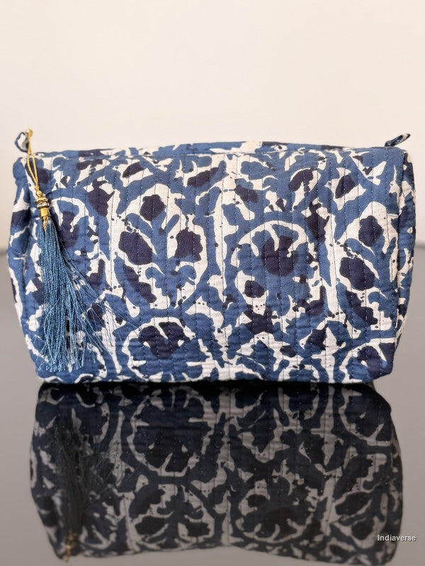 Blue and white patterned bag with a tassel on a reflective surface