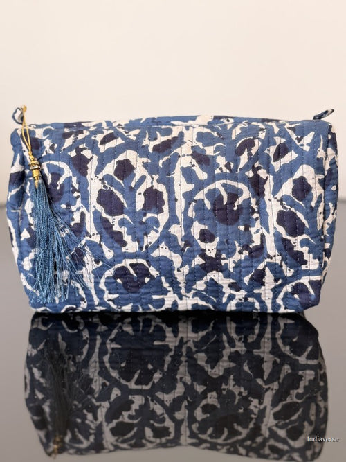 Blue and white patterned bag with a tassel on a reflective surface