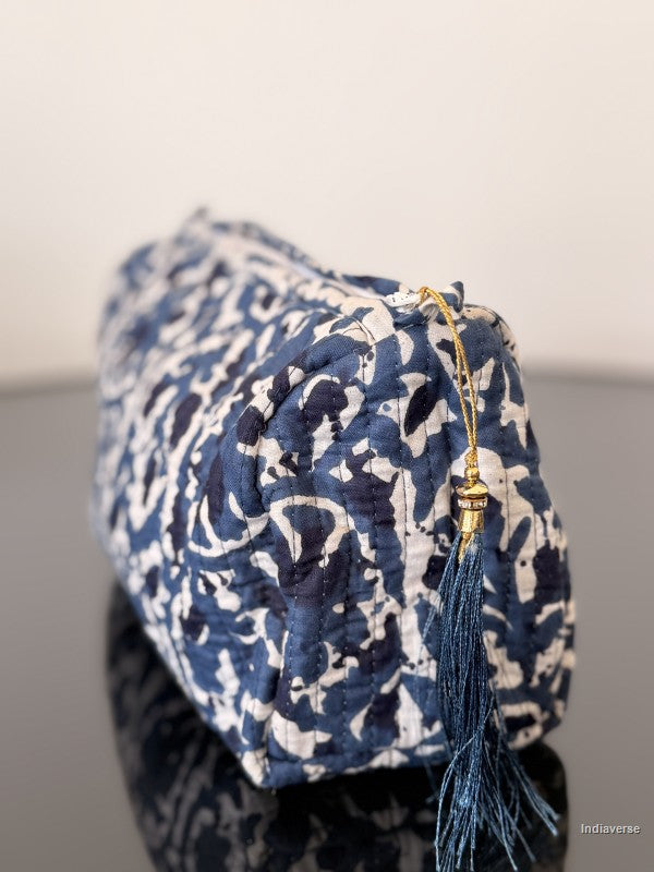Blue and white patterned pouch with a gold clasp and tassel on a neutral background