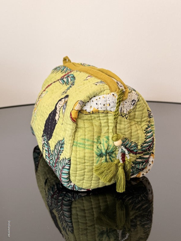 toiletry pouch with lime colored tassel sitting on a glass surface